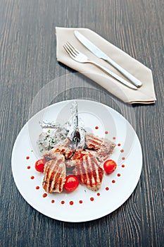 Grilled steak on a bone with tomatoes on a white plate. Hot Meat Dishes