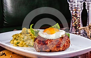 Grilled steak with fried egg and mashed potatoes on white plate