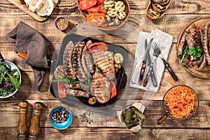 Grilled steak, grilled sausages, grilled vegetables on the wooden table