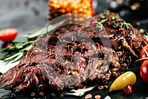Grilled Steak Ribeye Black Angus with corn and cherry tomatoes. Sliced Medium rare Fresh juicy delicious beef steak on a dark