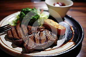 Grilled steak with salad on plate close-up. Juicy piece of beef meat.