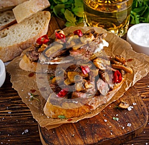 Grilled Steak Sandwich with mushrooms, goat`s cheese butter and rucola leaves on top. gold beer.