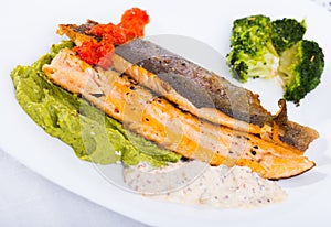 Grilled steelhead trout on white plate with broccoli and tartar sauce