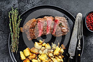 Grilled Striploin steak with potato, beef meat. Black background. Top view