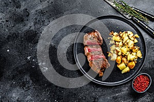 Grilled Striploin steak with potato, beef meat. Black background. Top view. Copy space