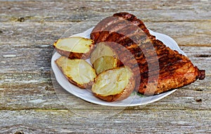 Grilled striploin steak with roasted potato on plate over wood table.