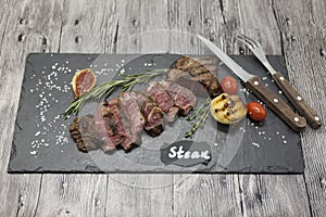 Grilled striploin steak on a stone plate with a fork and knife.