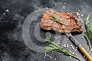 Grilled Striploin steak or strip new York on a meat fork. Black background. Top view. Copy space