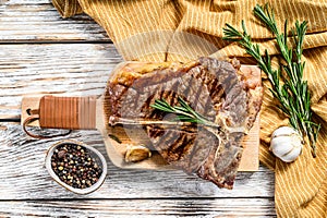 Grilled T bone steak on a chopping Board. Cooked tbone beef. White wooden background. Top view photo