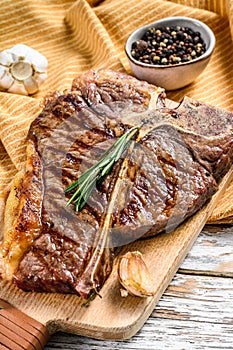Grilled T bone steak on a chopping Board. Cooked tbone beef. White wooden background. Top view