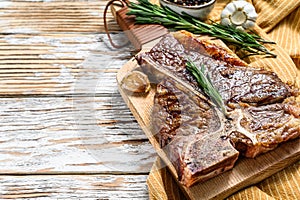 Grilled T bone steak on a chopping Board. Cooked tbone beef. White wooden background. Top view. Copy space photo