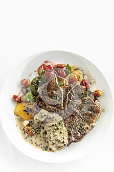 Grilled t-bone steak with peppercorn sauce and vegetables