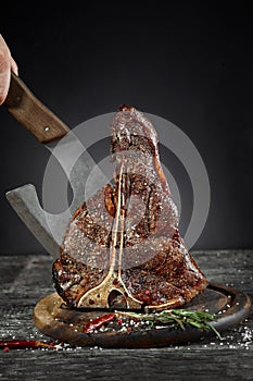 Grilled T-Bone Steak with salt and pepper on cutting board on dark background