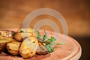 Grilled tasty potato placed on a wooden board together with herbs.