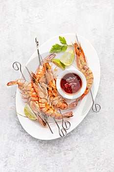 Grilled tiger prawns skewers served with hot  barbeque sauce, top down view