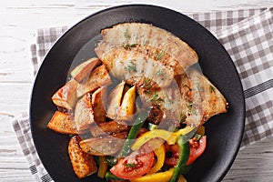 Grilled tilapia fillet, fried potatoes and a vegetable salad close-up. horizontal top view