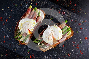 Grilled Toast witch Asparagus, Poached egg, bacon on stone background