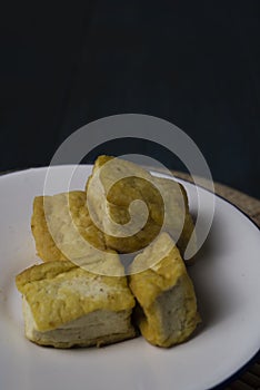 Grilled tofu on white plate over dark background