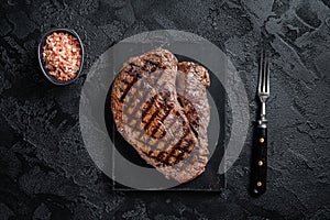 Grilled top sirloin or rump steak on a marble board. Black background. Top view