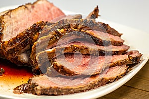 Grilled tri tip steak sliced on a white plate on the kitchen table photo