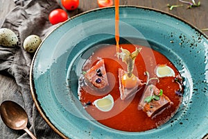 Grilled tuna with pepper and tomato sauce in plate on wooden background. Healthy food, seafood cuisine, close up