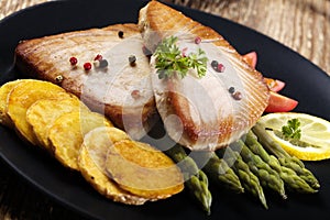 Grilled tuna steak served on asparagus with roasted potatoes