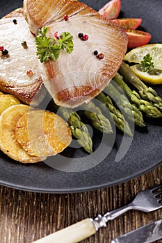 Grilled tuna steak served on asparagus with roasted potatoes