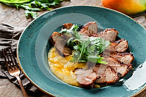 Grilled turkey fillet with mango puree in plate on wooden background. Summer food, meat dish, selective focus, close up