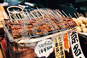 Grilled unagi or fresh water eel on sticks as street food at Nishiki market, Kyoto, Japan photo