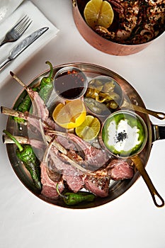 Grilled veal loin with vegetables and sauce and lemon in a copper pan