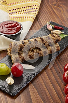 Grilled Veal minced meat with spices on black stone and wooden background photo