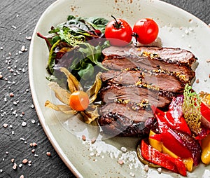 Grilled veal steak with salad and vegetables in plate on dark stone background. Hot Meat Dishes, top view