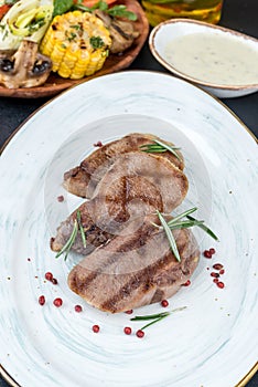 Grilled veal tongue served on a white plate