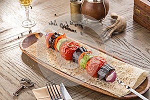 Grilled Vegetable Kebab with zucchini, tomato, eggplant and onion on lavash bread on wooden table