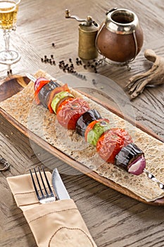 Grilled Vegetable Kebab with zucchini, tomato, eggplant and onion on lavash bread on wooden table