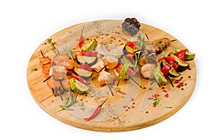 Grilled vegetable and meat skewers on a wooden table on a white background, top view