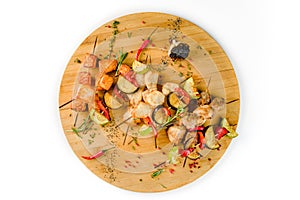 Grilled vegetable and meat skewers on a wooden table on a white background, top view