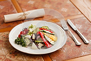 Grilled vegetables with cheese and herbs, seasoned with balsamic vinegar. served on a white round plate on a wooden table top