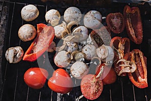 Grilled vegetables, chicken and pork meat on the open fire. Onions, mushrooms, tomatoes and red pepper on the grill grate.