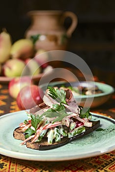 Grilled vegetables and meat served in a ceramic plate on a rustic wooden table with traditional tablecloth.