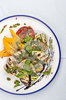 Grilled vegetables - tomatoes, zucchini, eggplant, sweet pepper, mushrooms. In a white plate
