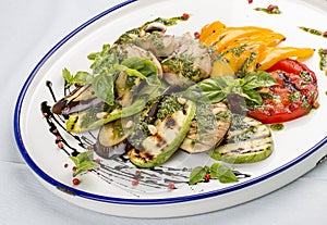 Grilled vegetables - tomatoes, zucchini, eggplant, sweet pepper, mushrooms. In a white plate