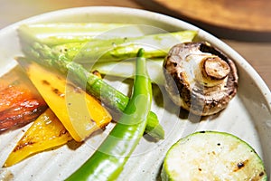 Grilled vegetables in white plate. Pepper, mushroom, zuchini and asparagus close up. Selective focus