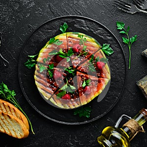 Grilled watermelon with raspberries and parsley on a black plate. Top view.