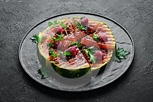 Grilled watermelon with raspberries and parsley on a black plate. Top view.