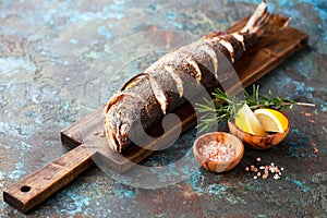 Grilled whole humpback salmon fish with lemon on a wooden cutting board