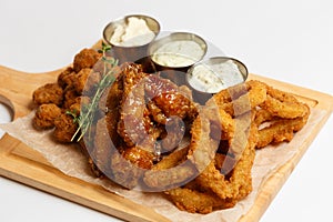 Grilled wings, deep-fried squid rings, appetizers with a sauces