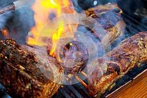 grilling baby back pork ribs over flaming grill