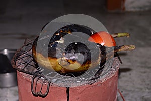 Grilling of Brinjal and tomato on coal stove or charcoal stove  or mitti ka chulha or charcoal chulha or coal chulha or charcoal photo