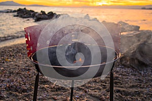 Grilling burgers on a small metal portable charcoal grill on the shores of Lac Leman in Switzerland during early winter evening